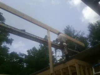 Carpenter setting a ridge beam over a new addition frame — Ice Dam Removal by Roofing Brothers in Timnath
