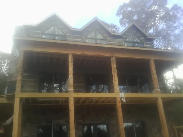 Dormers and porch framing on a large log home under construction — Roof Coating work by our crew in Timnath