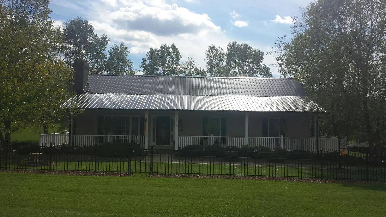 Gray metal roof on a brick ranch with a full width front porch — Gutter Guard Installation work by our crew in Timnath