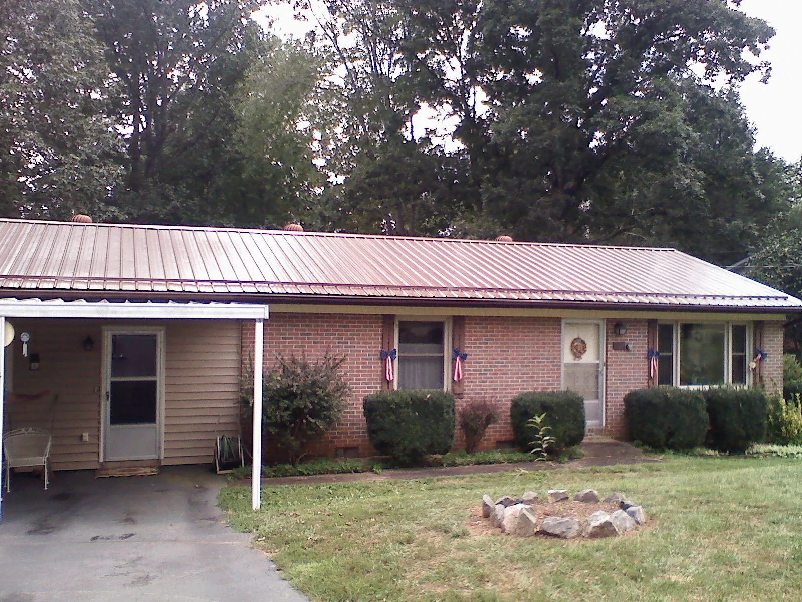 Bronze metal roof and carport on a brick ranch home — Roof Repair work by our crew in Timnath