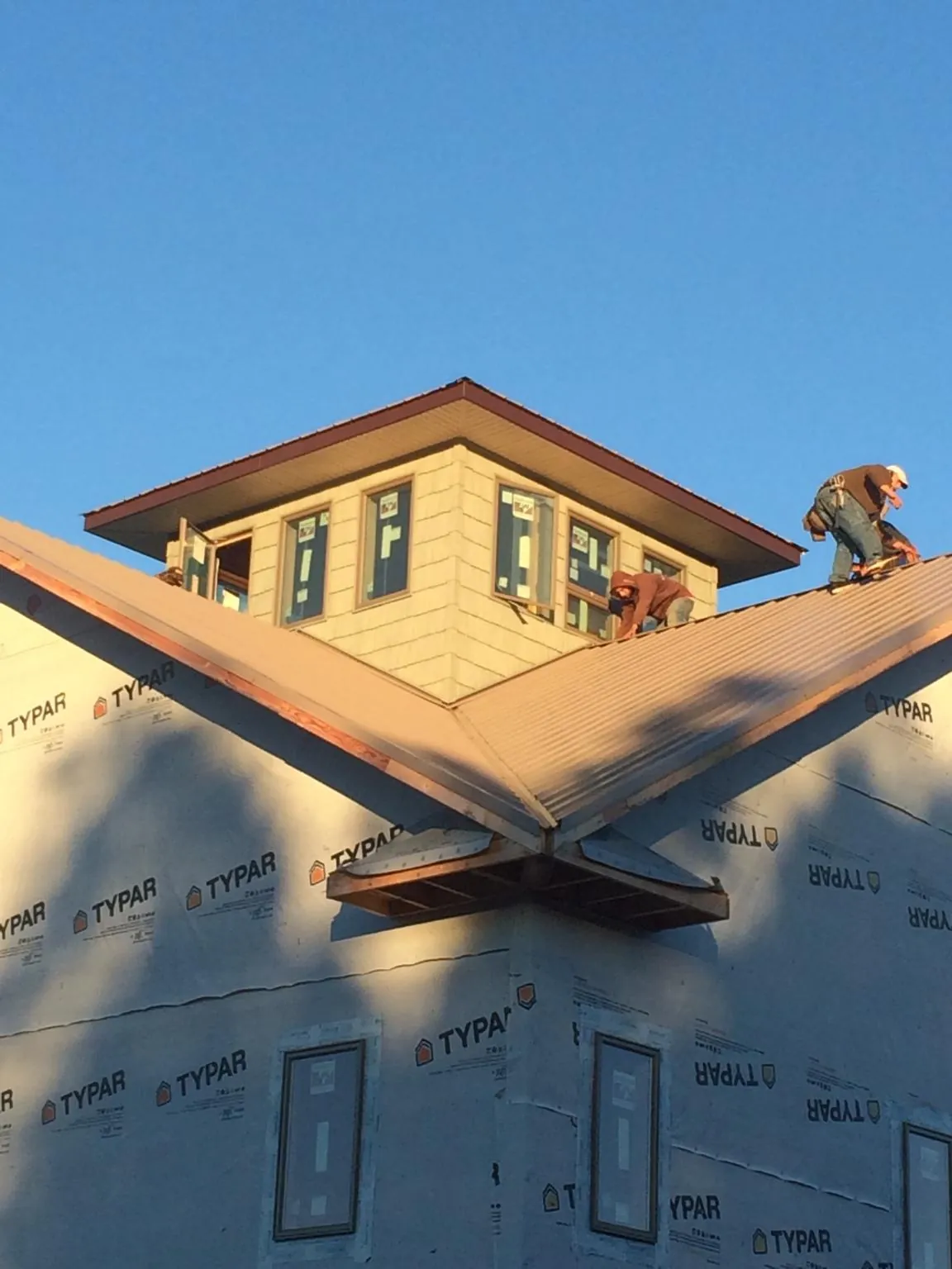Roofers working around a rooftop cupola on a new metal roof at sunset — Roof Waterproofing in Timnath by Roofing Brothers